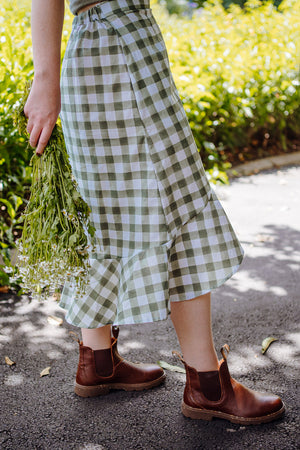 The Rosalie skirt in green cotton gingham, showing side view with high low hem